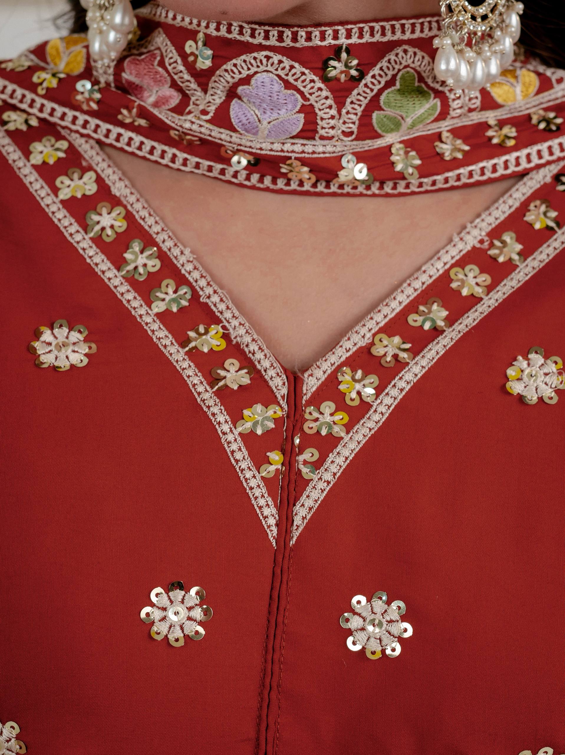 Resplendent Rust Orange Peplum Kurti and Flared Palazzo Suit Set Adorned with Intricate Multicolored Floral Embroidery, Sequin Accents, and Ornate Scalloped Borders
